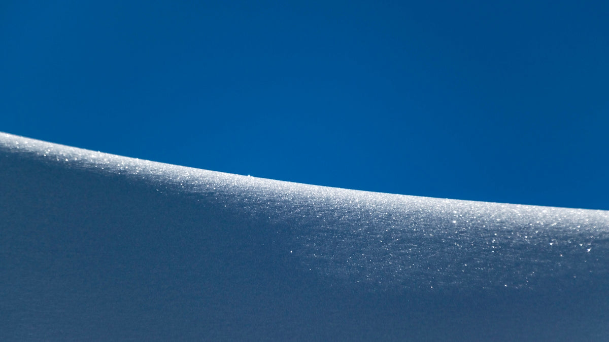 a person riding a snowboard down a snow covered slope