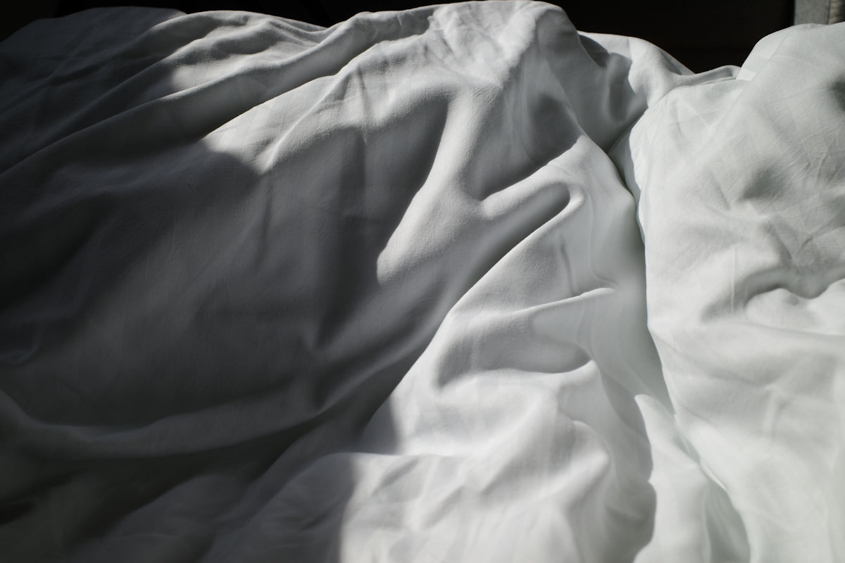 an unmade bed with white sheets and white sheets
