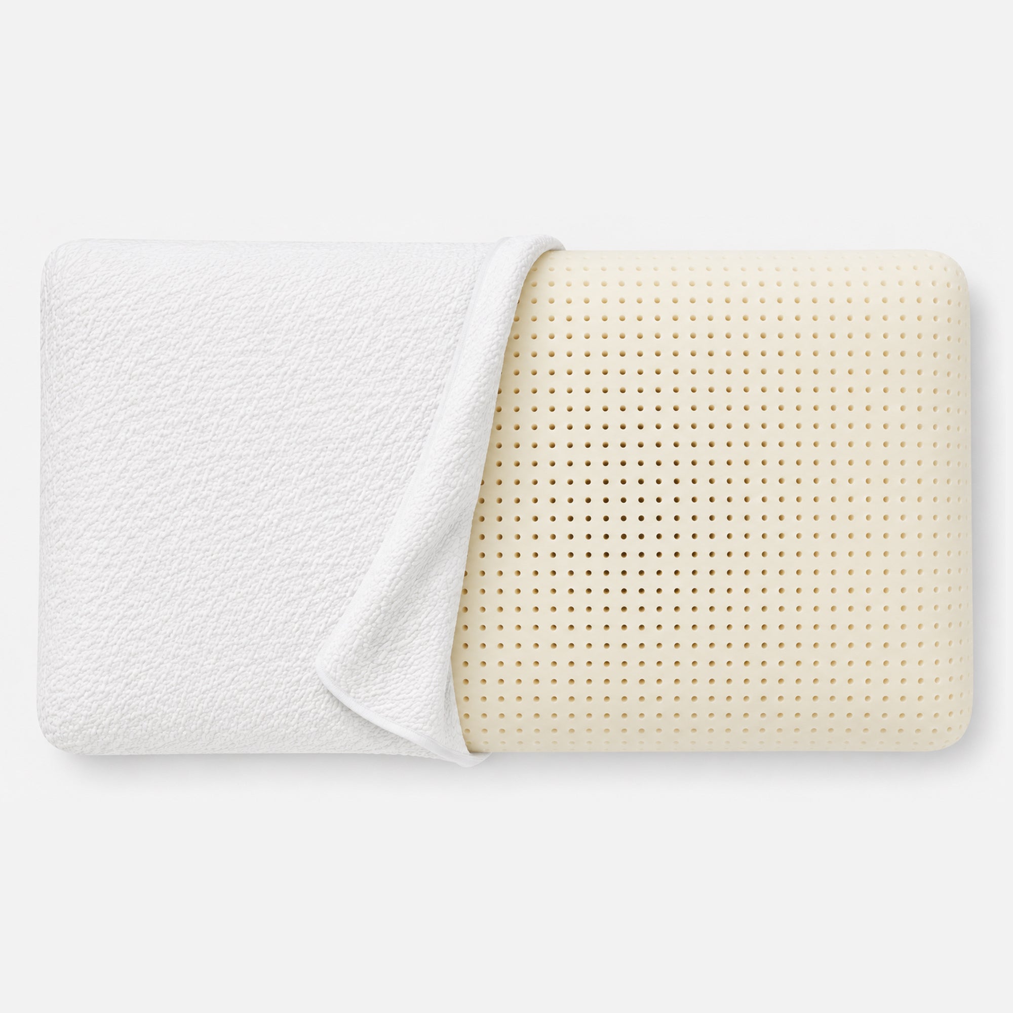A natural latex pillow with a textured white fitted sheet partially pulled back to reveal the perforated cream-colored inner surface, set against a clean white background.