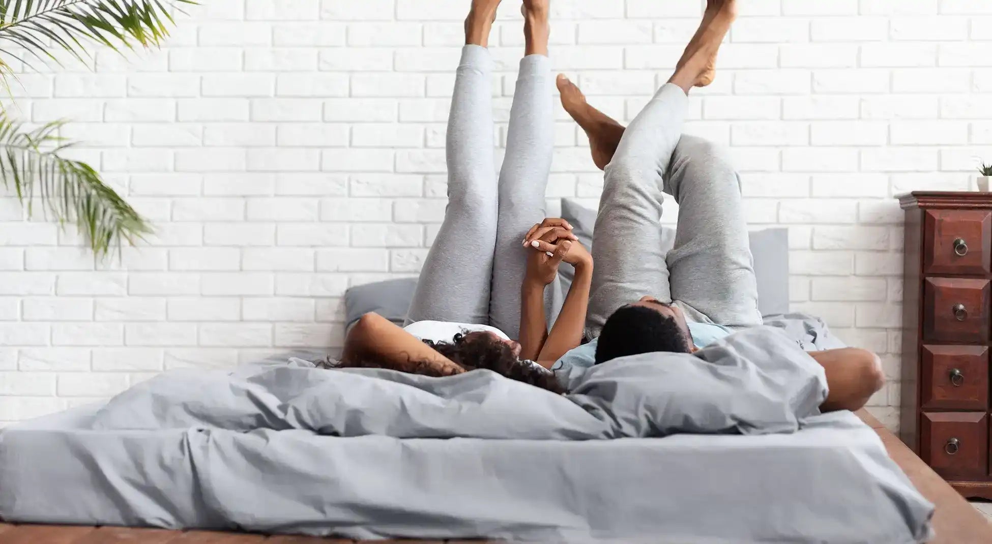 Couple lying on bed with legs up.