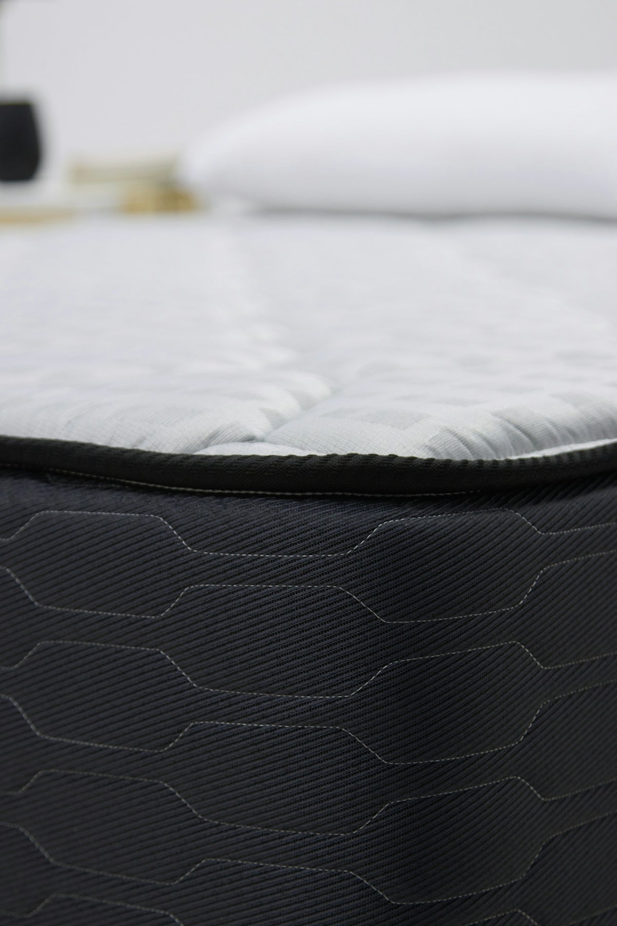 Close-up of a dark gray mattress with white bedding.
