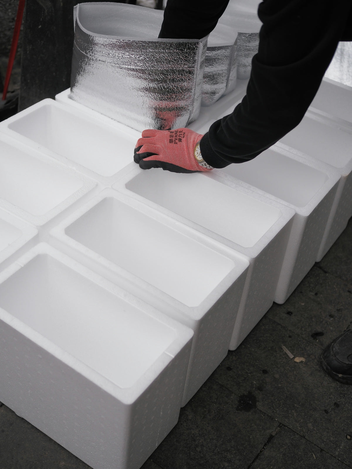Hands arranging white styrofoam boxes in a line.