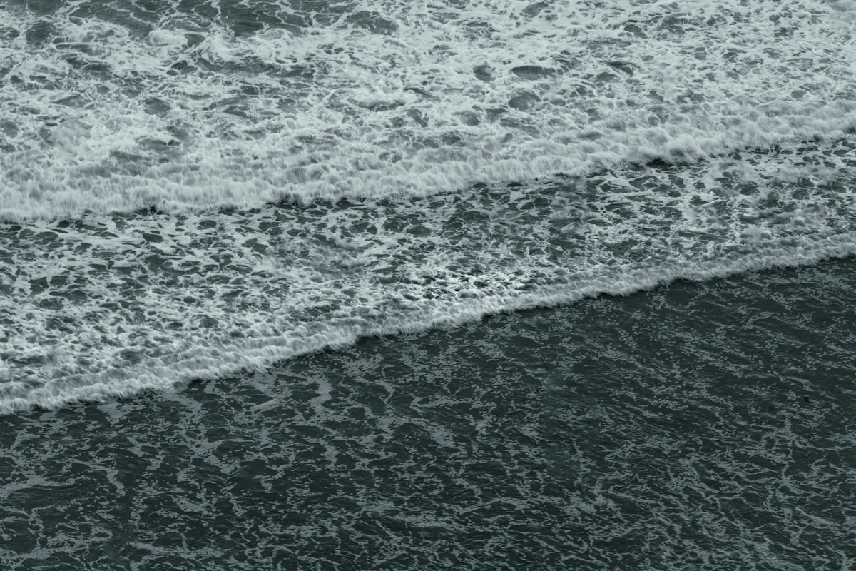 White sea foam rolling over dark ocean waves in a rhythmic pattern